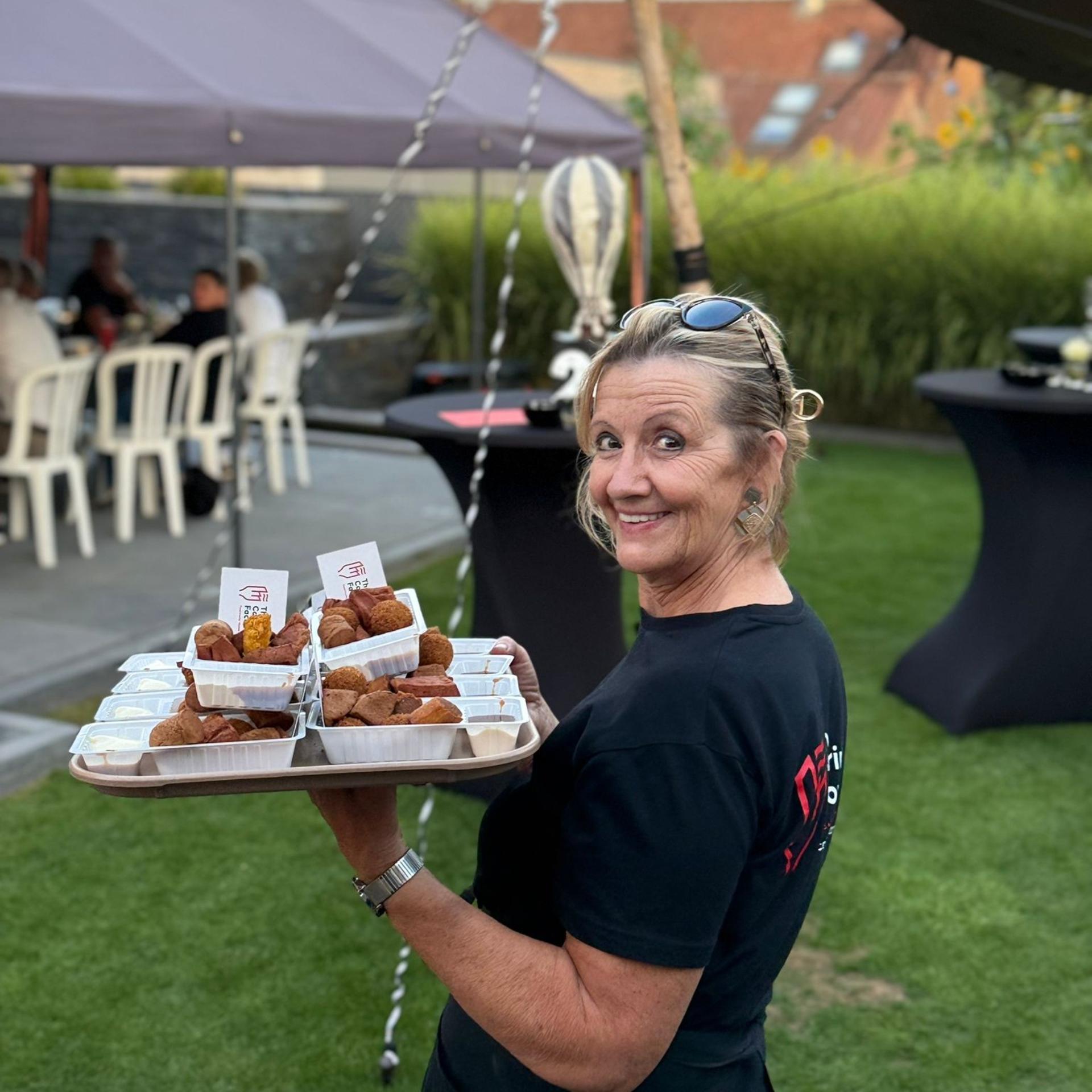Medewerker van De Snackcar serveert verse frituursnacks tijdens een feest of evenement.
