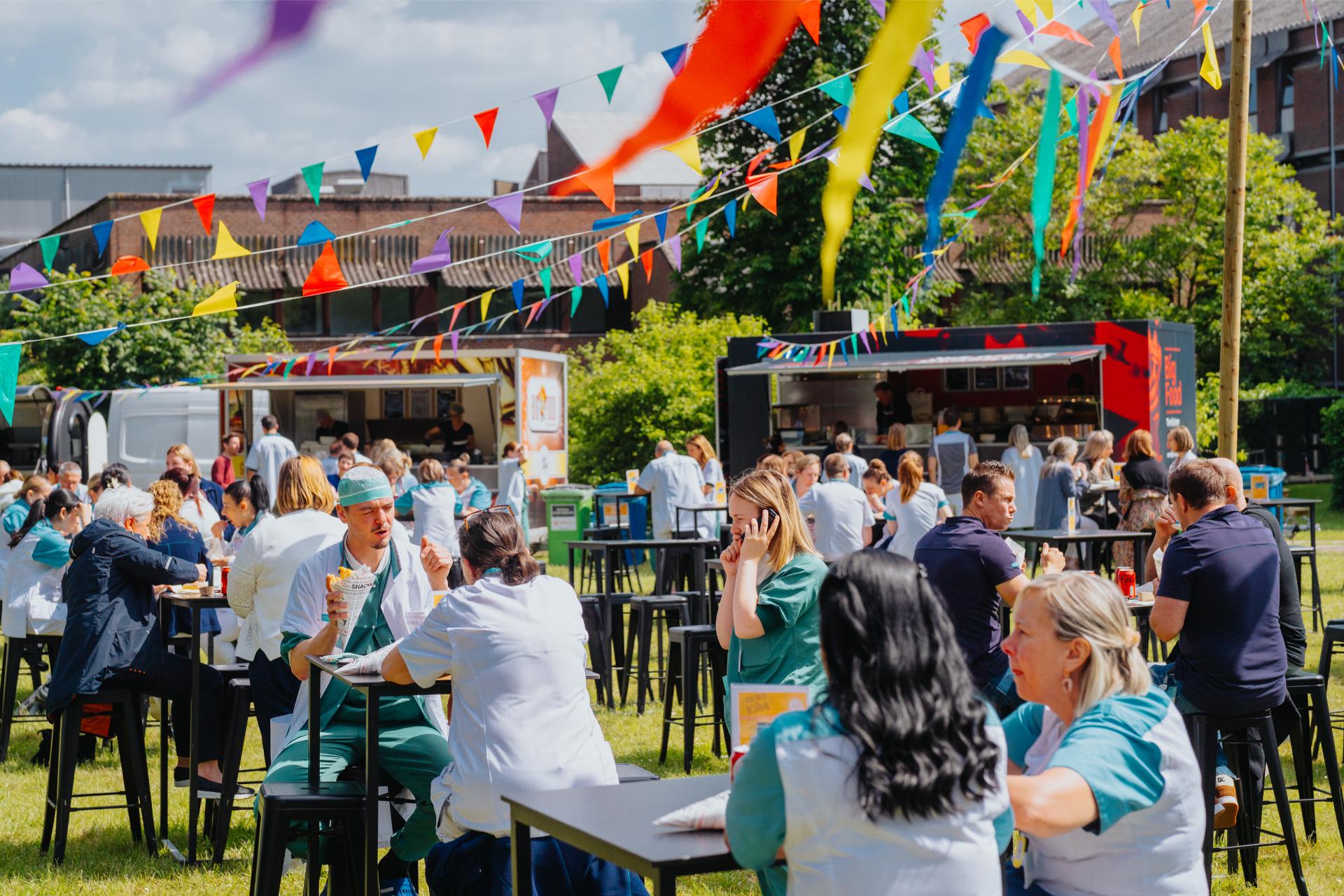 Mobiele frituren van De Snackcar verzorgen catering tijdens een druk bedrijfsfeest in openlucht.